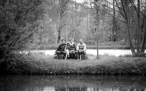 Schwarz-weißes Familienporträt von vier Personen – Eltern mit zwei Kindern – die auf einer Bank am Ufer eines Sees in natürlicher Umgebung sitzen. Ein harmonisches Outdoor-Familienbild, professionell festgehalten von Michael Schalansky Fotografie in Erfurt.